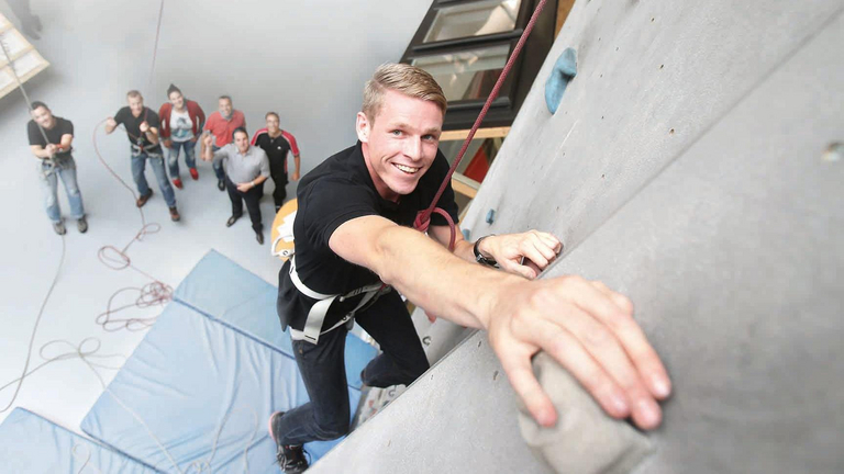 A young man climbs up a climbing wall