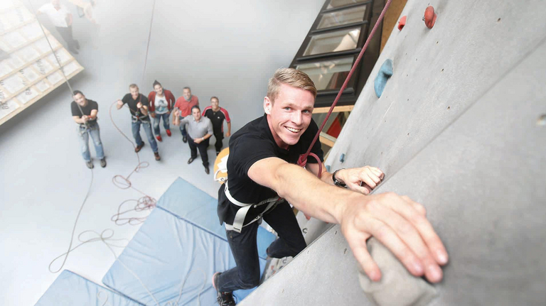 A young man climbs up a climbing wall