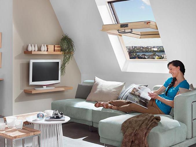 A woman lies on the couch, reads a brochure and airs the living room with her RotoQ wooden swing window.
