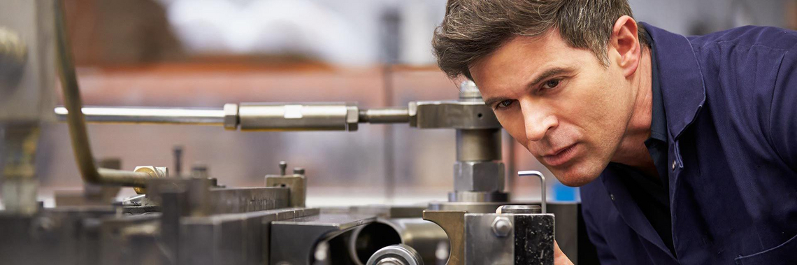 A man takes a close look at a part of a machine.