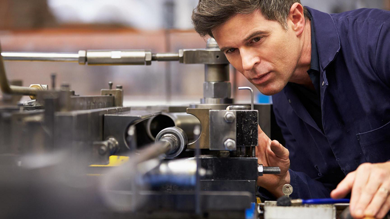 A man takes a close look at a part of a machine.